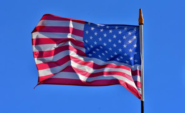Det amerikanske flagget blafrer i vinden med blå himmel bak