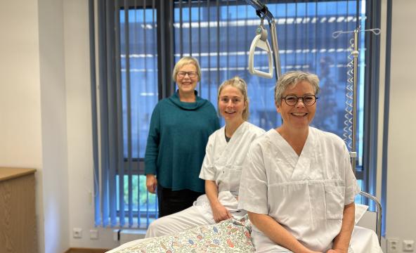 Bilde av tre kvinner ved sykeseng. Foto: Lene Loe.