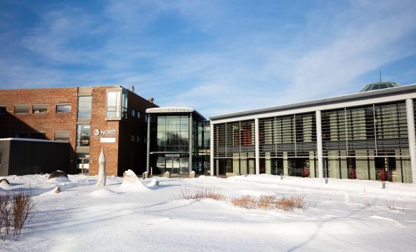 Universitetsbygg i vinterlandskap. Snø og blå himmel. Foto