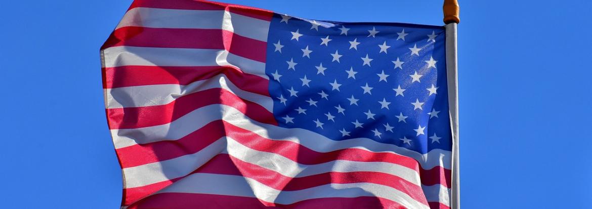 Det amerikanske flagget blafrer i vinden med blå himmel bak