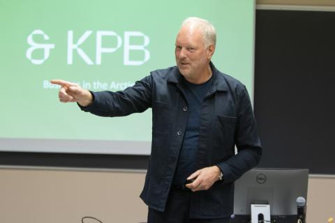 Director of Kunnskapsparken Bodø, Erlend Bullvåg, stands at the front of a classroom and talks, while he raises his hand and points to his right.
