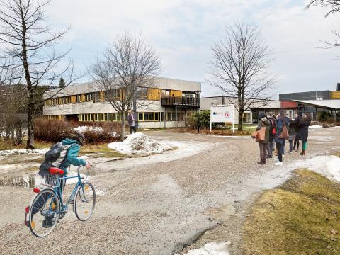 Universitetsbygg med syklist og mennesker utenfor. Foto/illustrasjon.