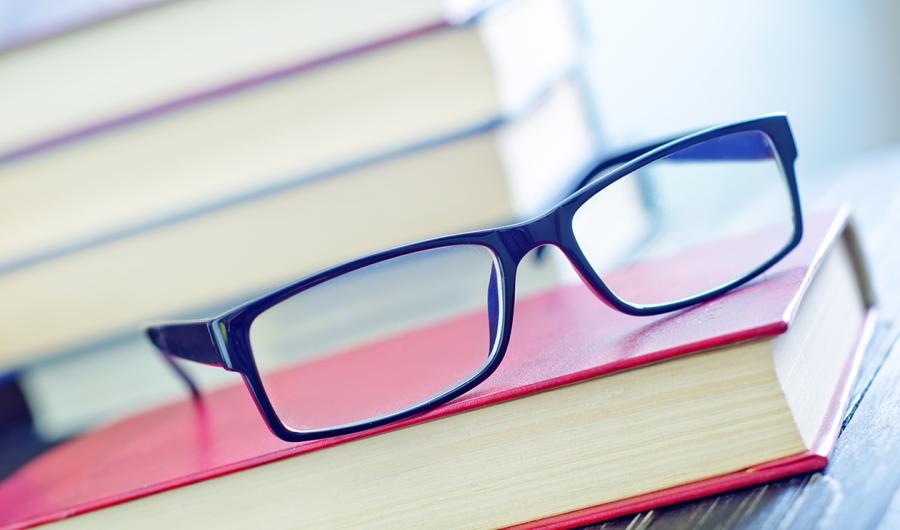 Et par briller som ligger oppå ei bok.